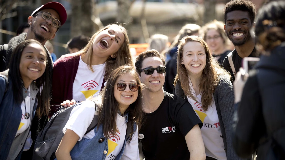 A group of smiling people poses together for a photo outdoors.