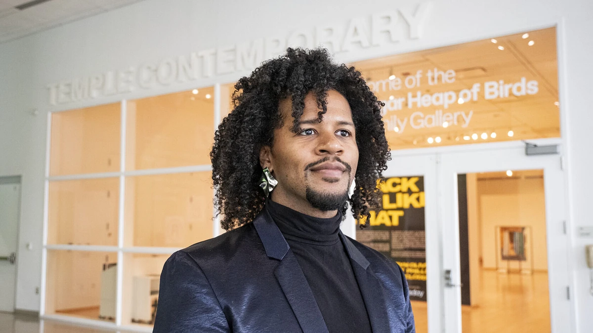 A person with curly hair stands in front of the Temple Contemporary gallery entrance.