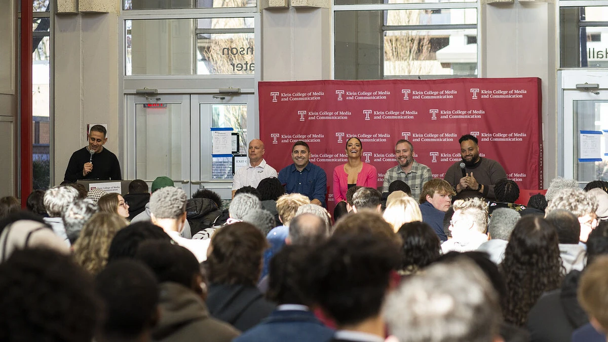 A speaker addresses a full audience in front of a panel at Klein College of Media and Communication.