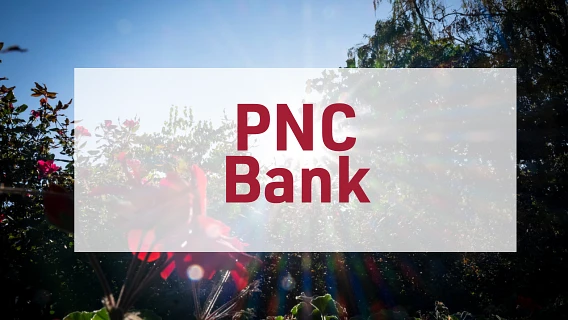 The image features the text "PNC Bank" in red on a white rectangle overlaying a background of sunlight shining through foliage.